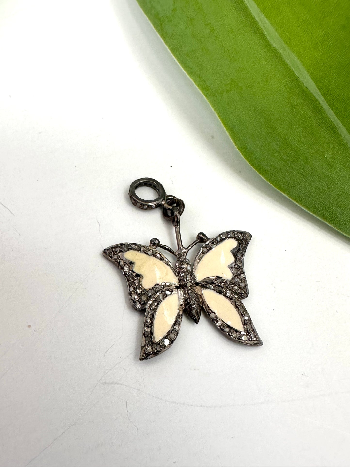 Butterfly-shaped pendant with white wings and black details on a white background