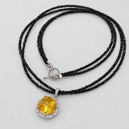 Black spinel and citrine pendant necklace on white background, handmade silver design