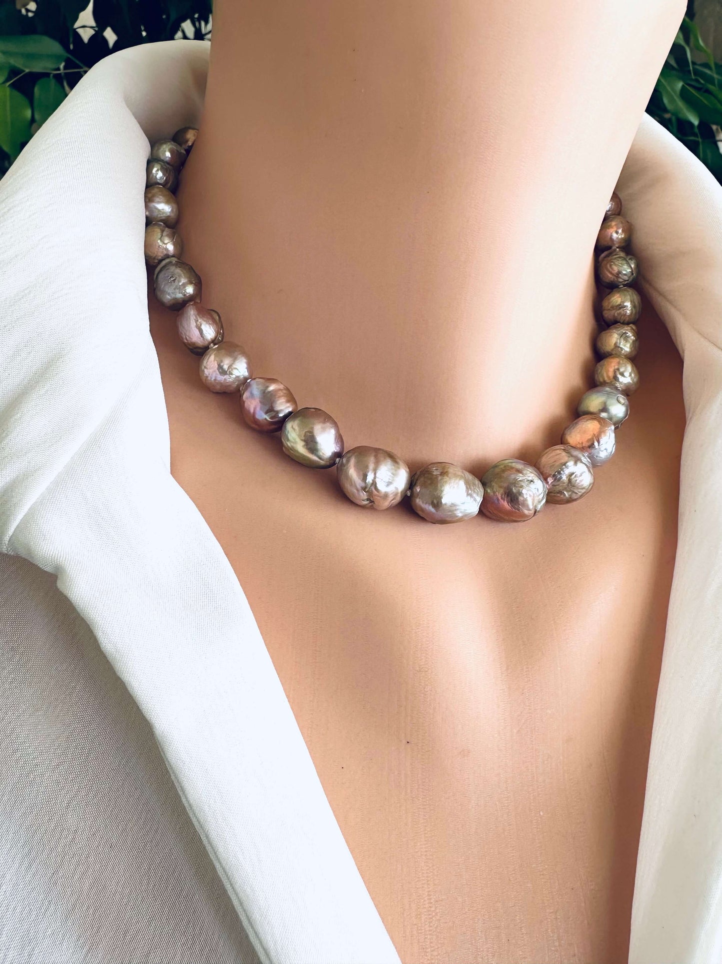 Necklace with large beads on a mannequin wearing a white outfit.