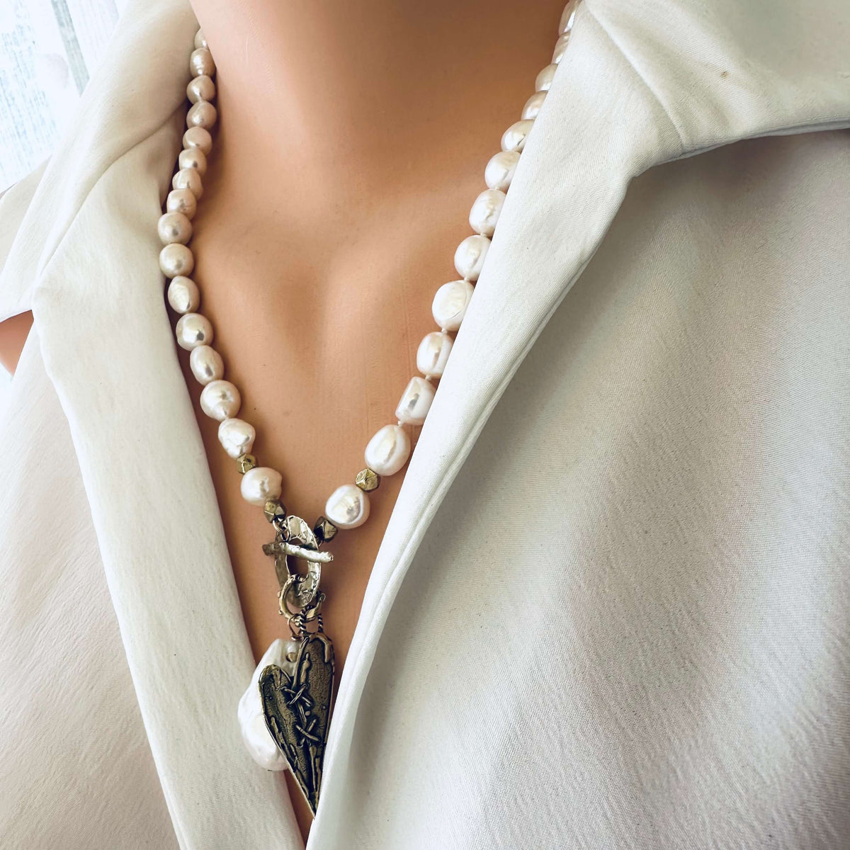 Pearl toggle necklace with heart pendant displayed on mannequin