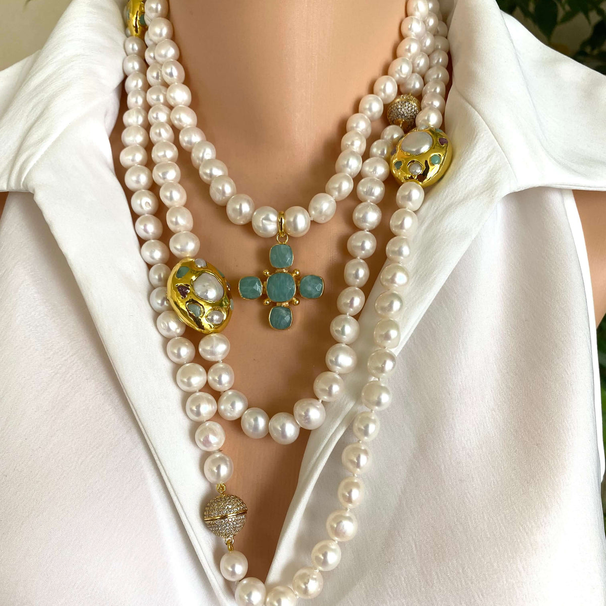 White pearl necklace with gold accent displayed on a model, featuring multiple strands and a decorative centerpiece.