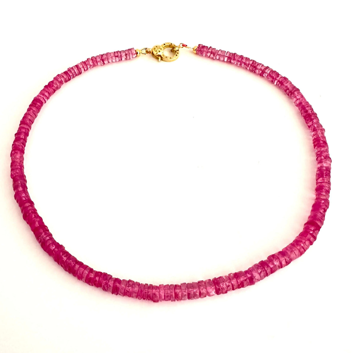 A beaded necklace made of small, faceted magenta-pink beads with a gold clasp, displayed on a plain white background.