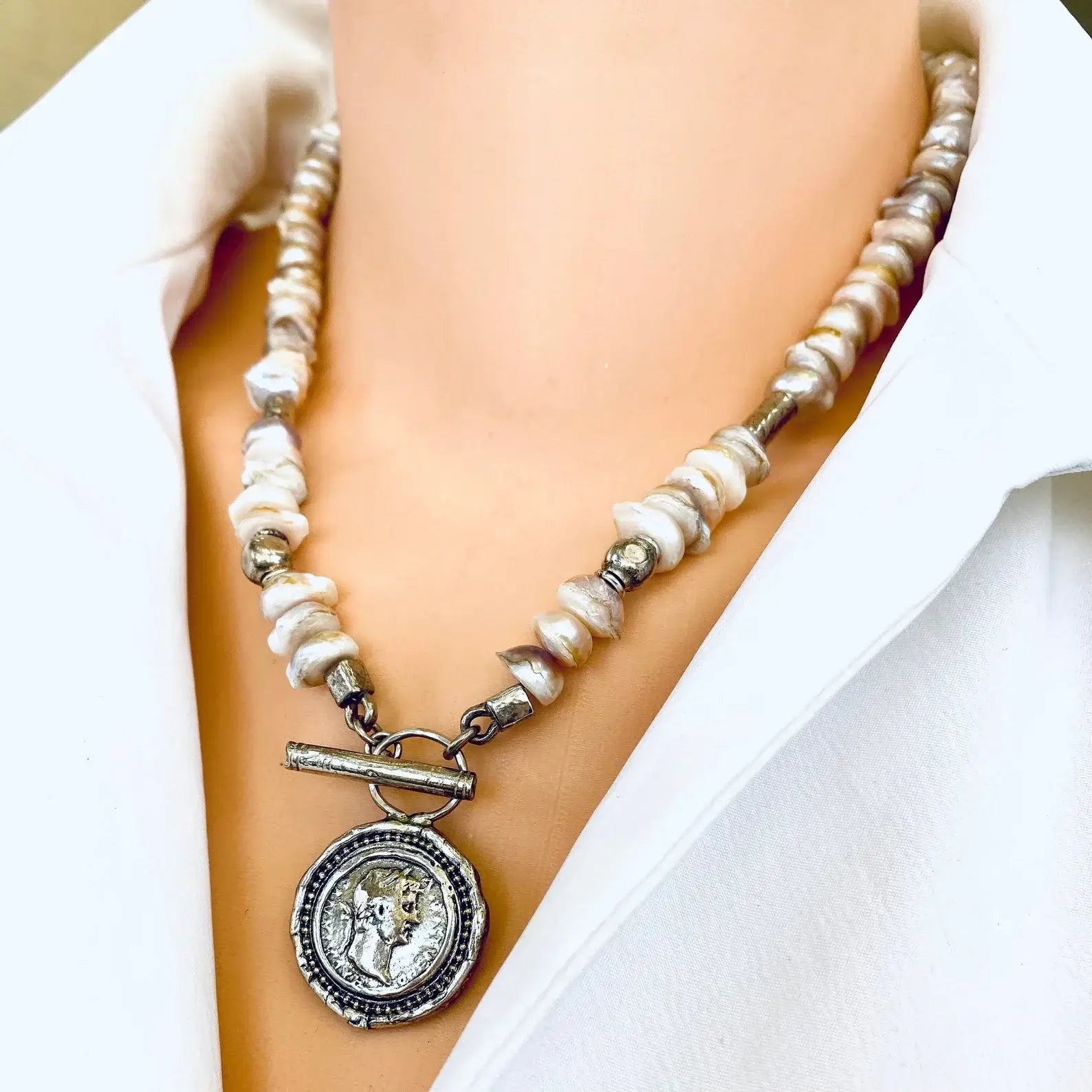 Lavender baroque pearl necklace with silver Roman coin toggle clasp displayed on mannequin.