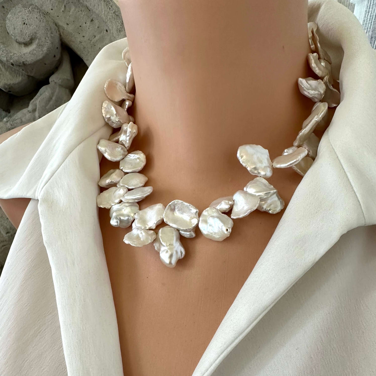 Side view of white keshi pearl necklace with flower clasp displayed on mannequin