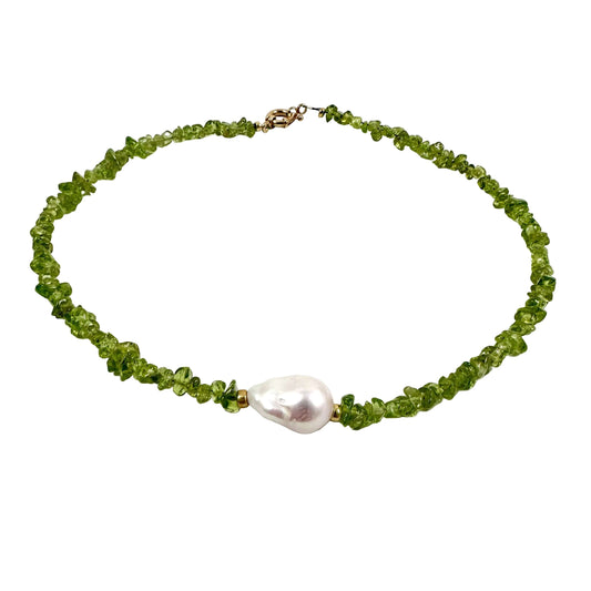 A beaded necklace made of small green faceted beads with a large, irregular white pearl pendant, displayed on a clean white background.