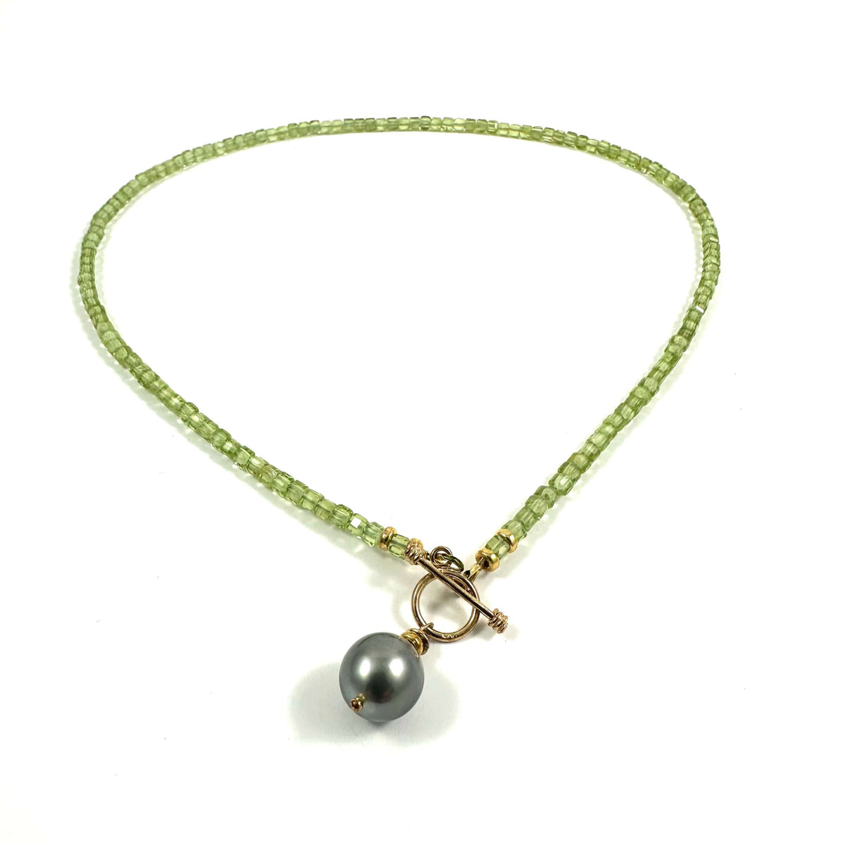 A beaded necklace featuring light green square beads, a gold-tone toggle clasp, and a single dark gray pearl pendant, displayed on a clean white background.