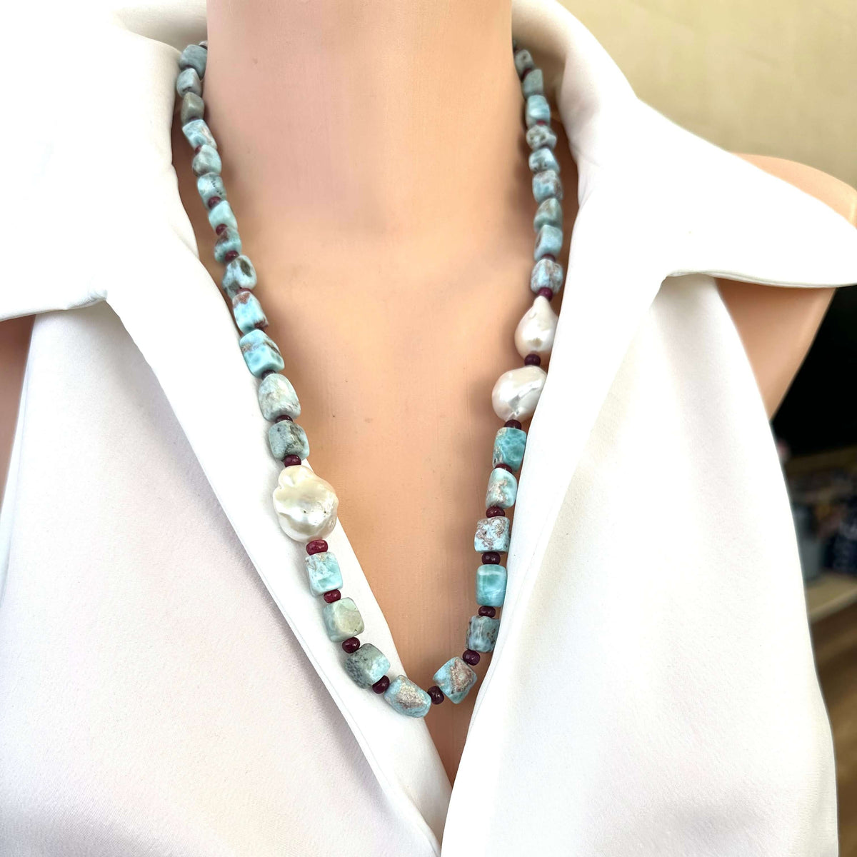 Front close-up of larimar ruby and baroque pearl necklace on mannequin display