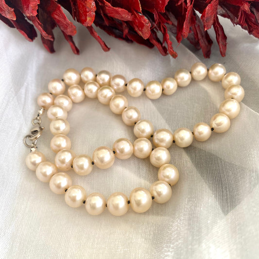 Off white pearl choker necklace displayed on white cloth
