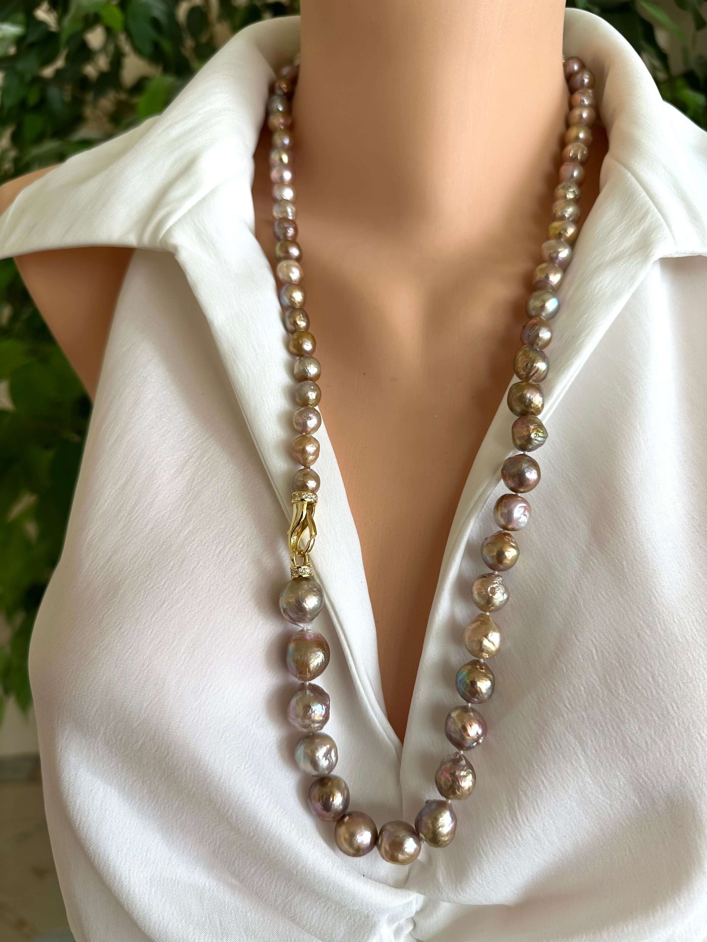 Pearl necklace on a mannequin wearing a white shirt with a blurred green background