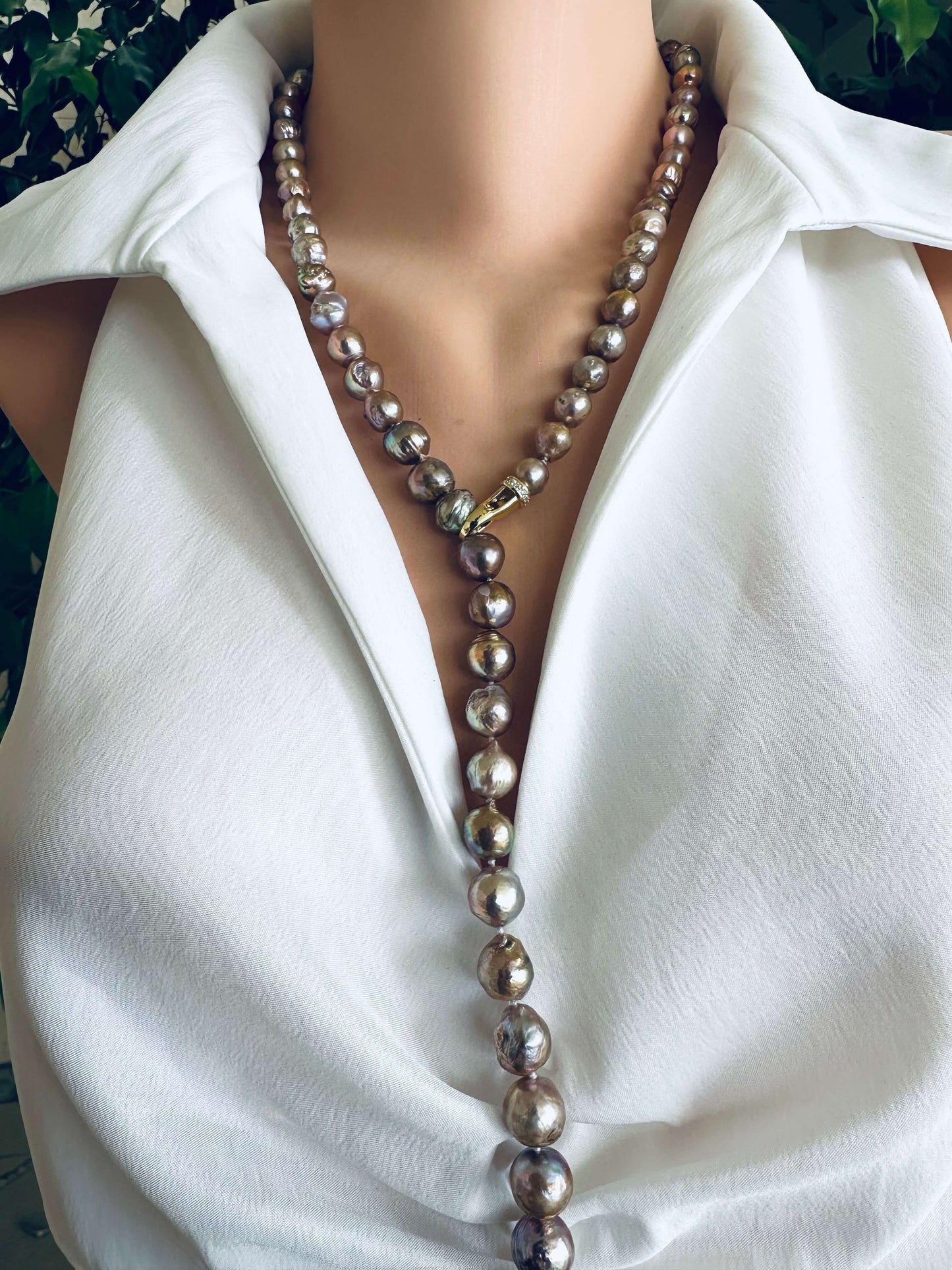 Pearl necklace worn by a person in a white shirt with a blurred background