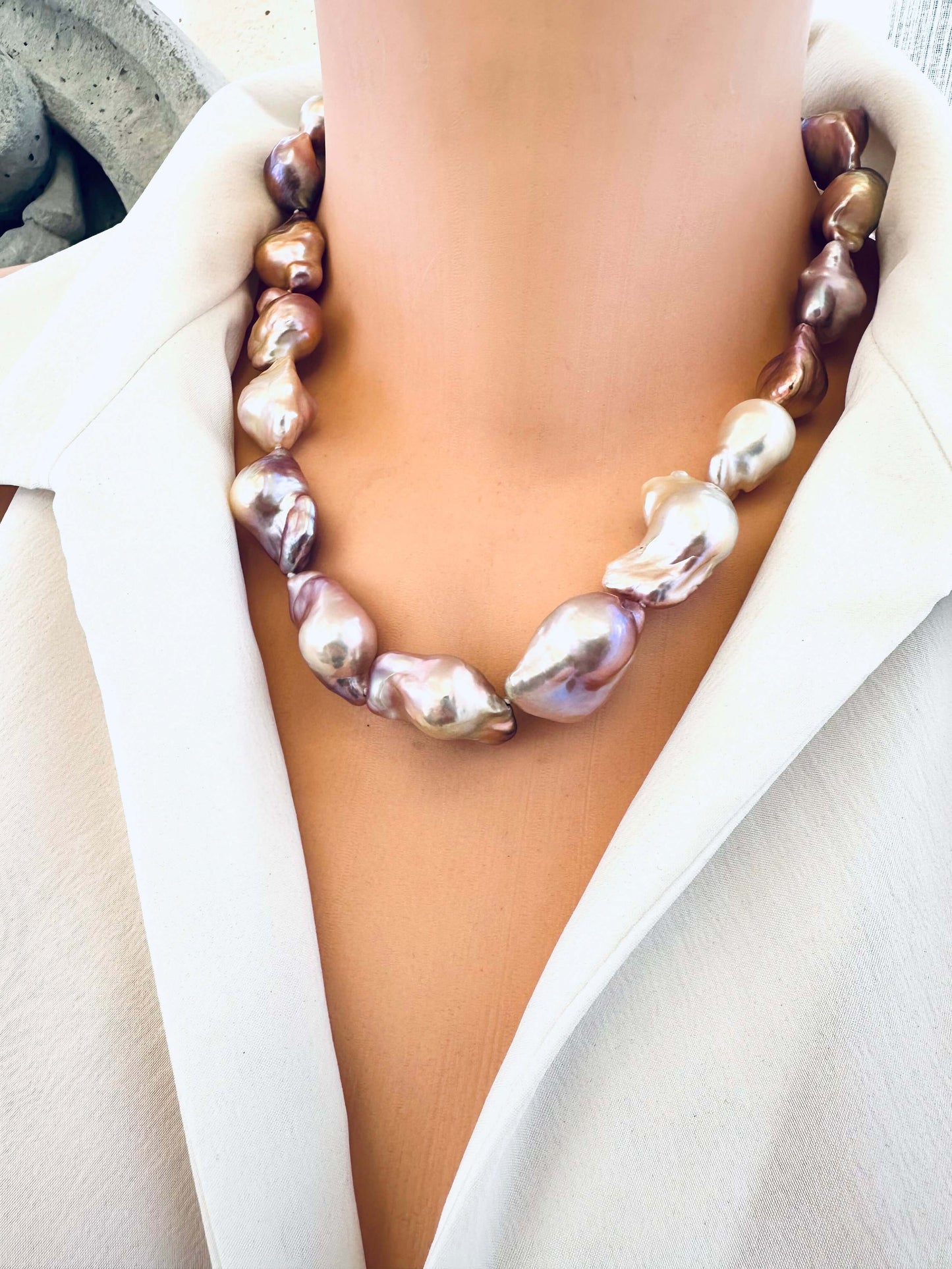 Pearl necklace worn by a person in a white outfit