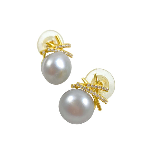 A pair of gold stud earrings featuring a large gray pearl and a gold bow-shaped setting accented with small clear crystals, shown on a white background.