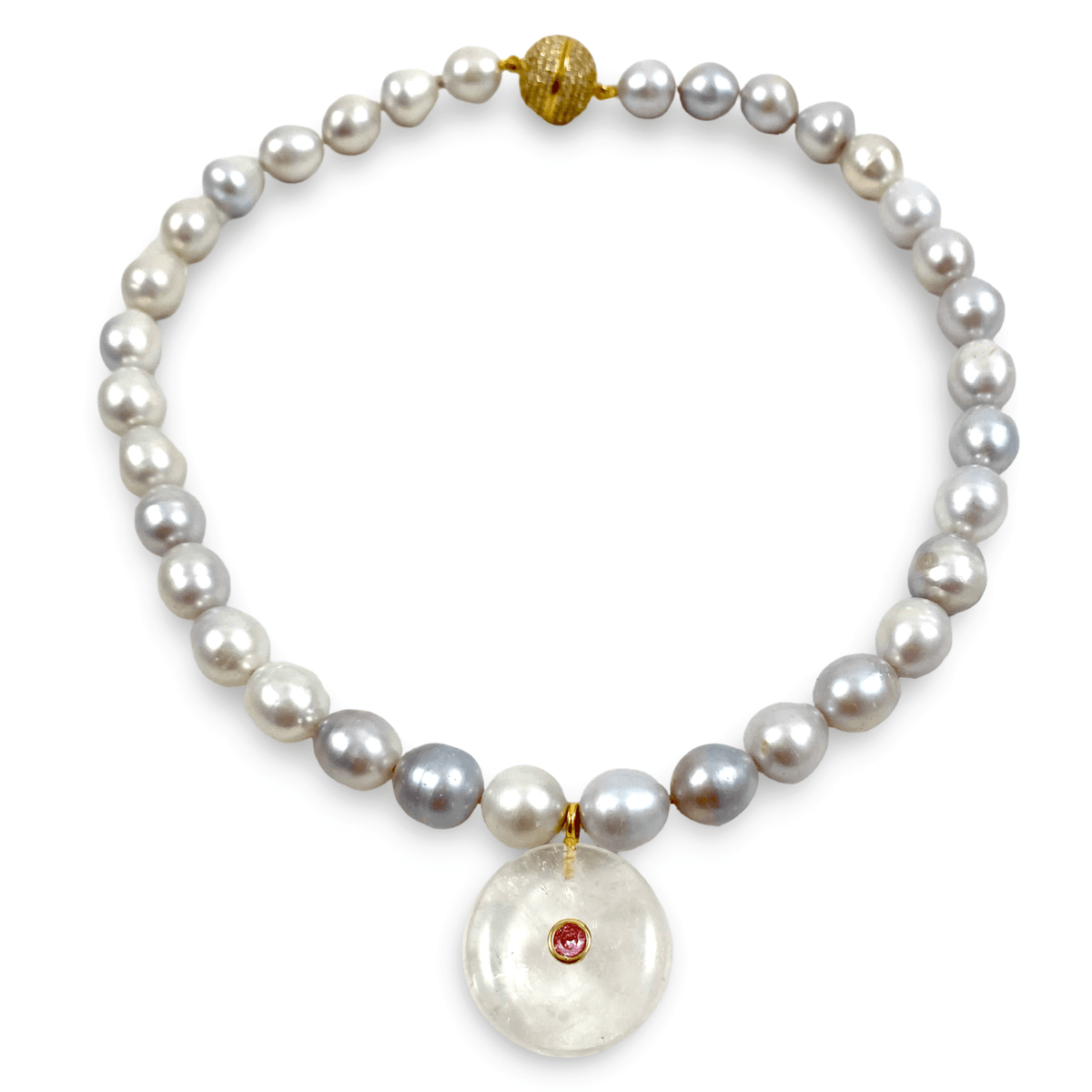 A pearl necklace with irregular white and gray pearls, accented by a gold clasp, a gold bead, and a large round white stone pendant featuring a small red gemstone, shown on a plain white background.