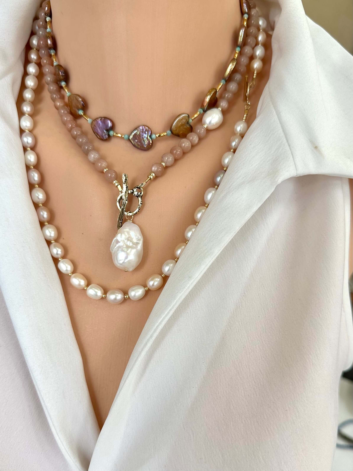 Sunstone necklace layered with two pearl necklaces on mannequin, frontal view