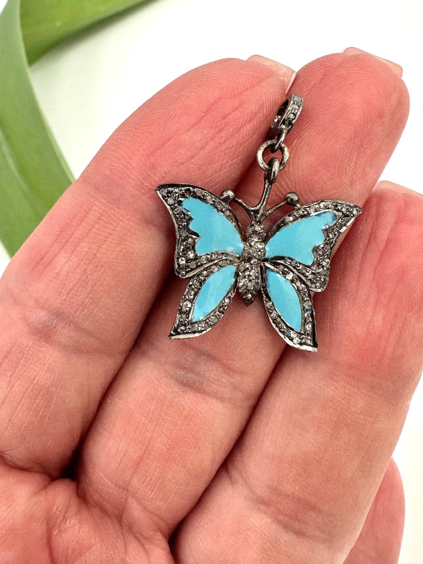 Butterfly pendant with blue wings held in a hand