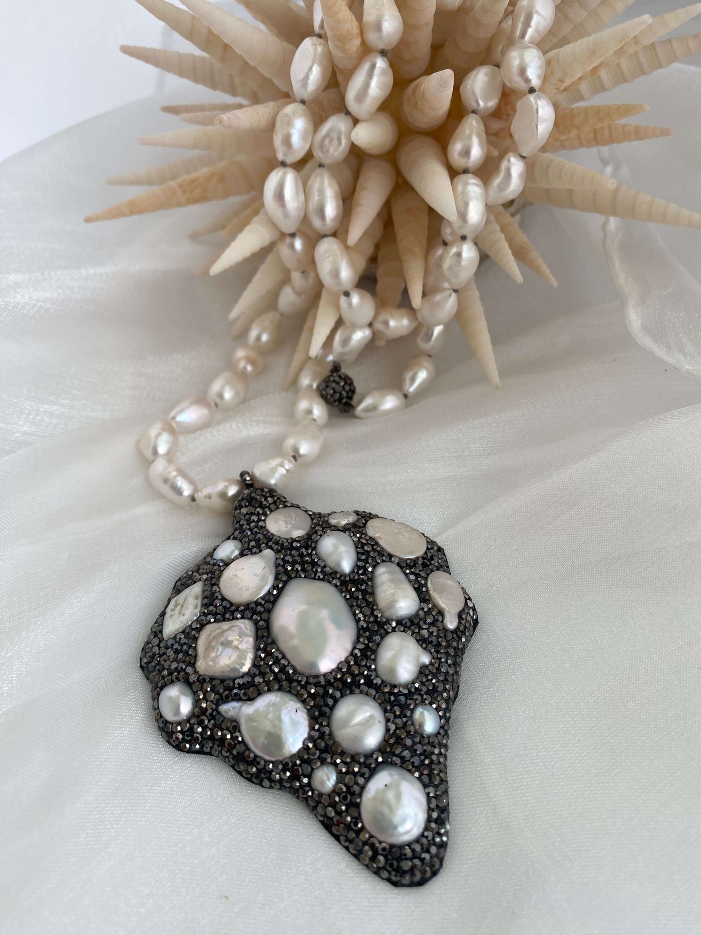 Pearl necklace and leaf-shaped pearl jewelry piece on a white background