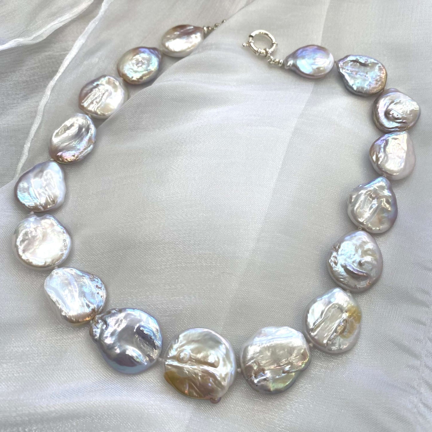 Detail of large coin pearl necklace pearls on white background, handmade jewelry