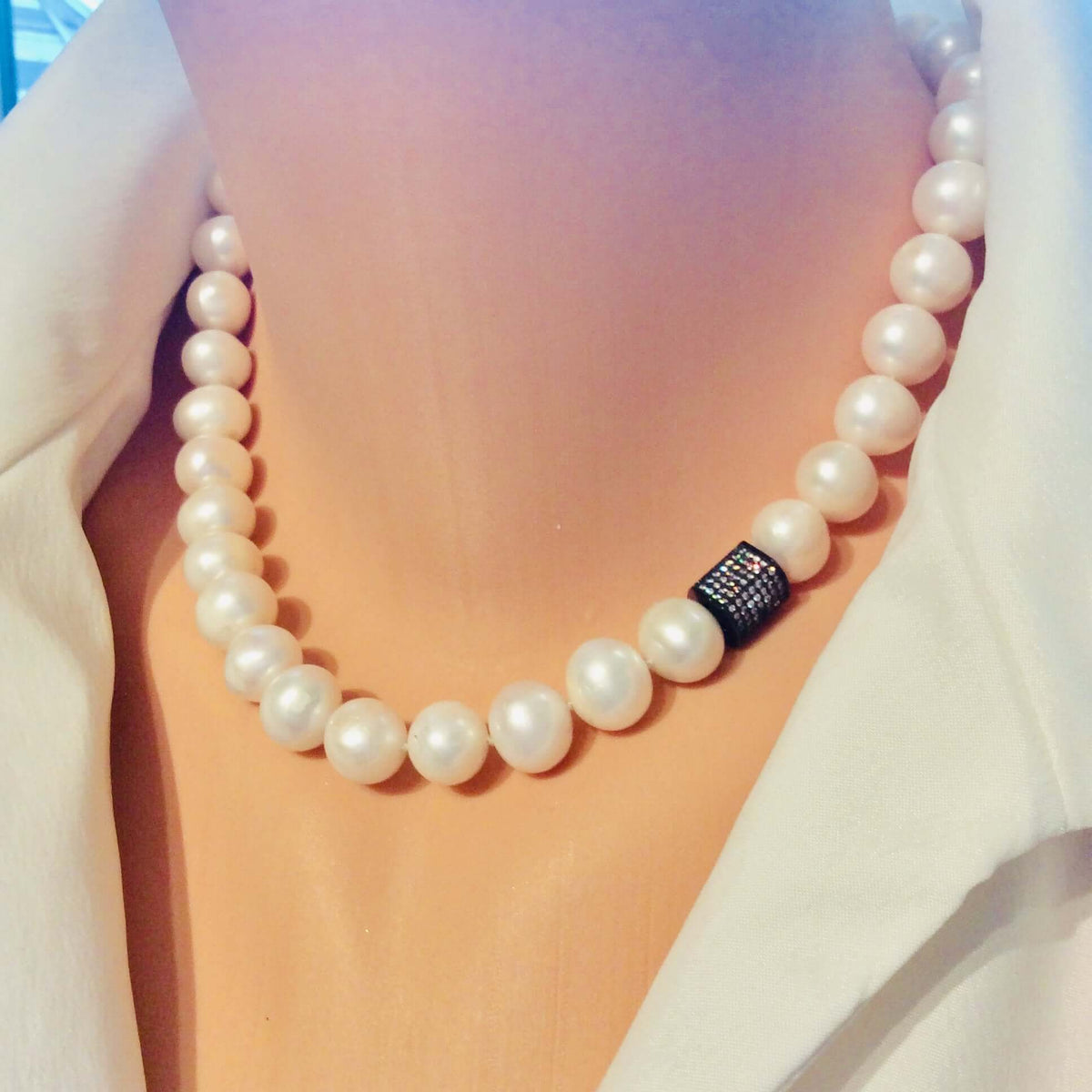Pearl necklace with a black clasp on a blurred background