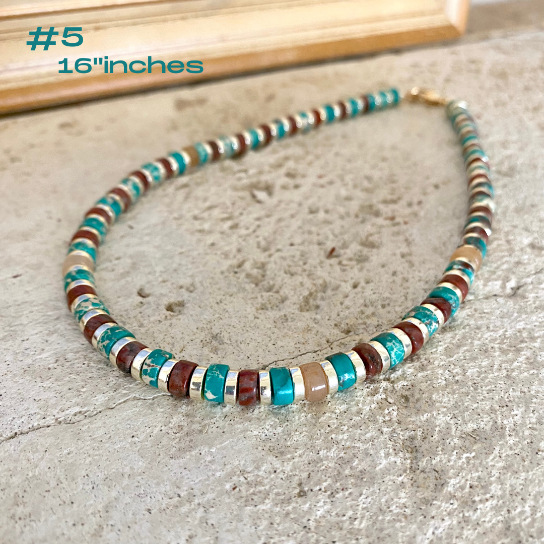 Gemstone choker necklace with multi color beads and hematite on a stone surface, showcasing vibrant tube-shaped beads.