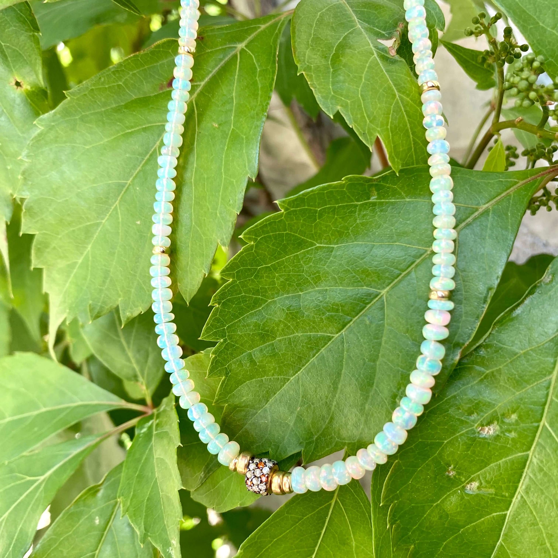 Ethiopian opal necklace hanging on green leaves, smooth rondelle opal beads with gold vermeil details