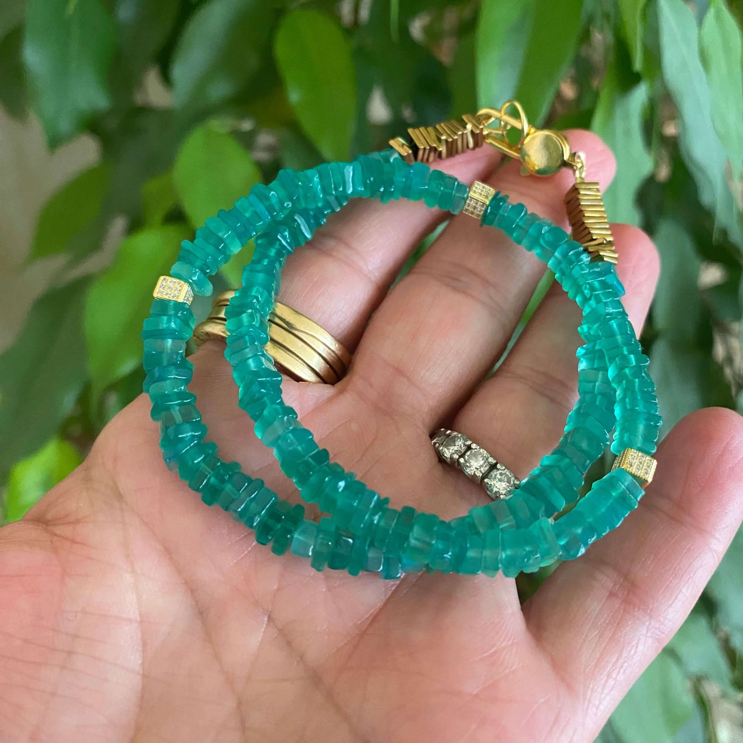 Green onyx choker necklace held in hand highlighting heishi onyx beads and gold accents