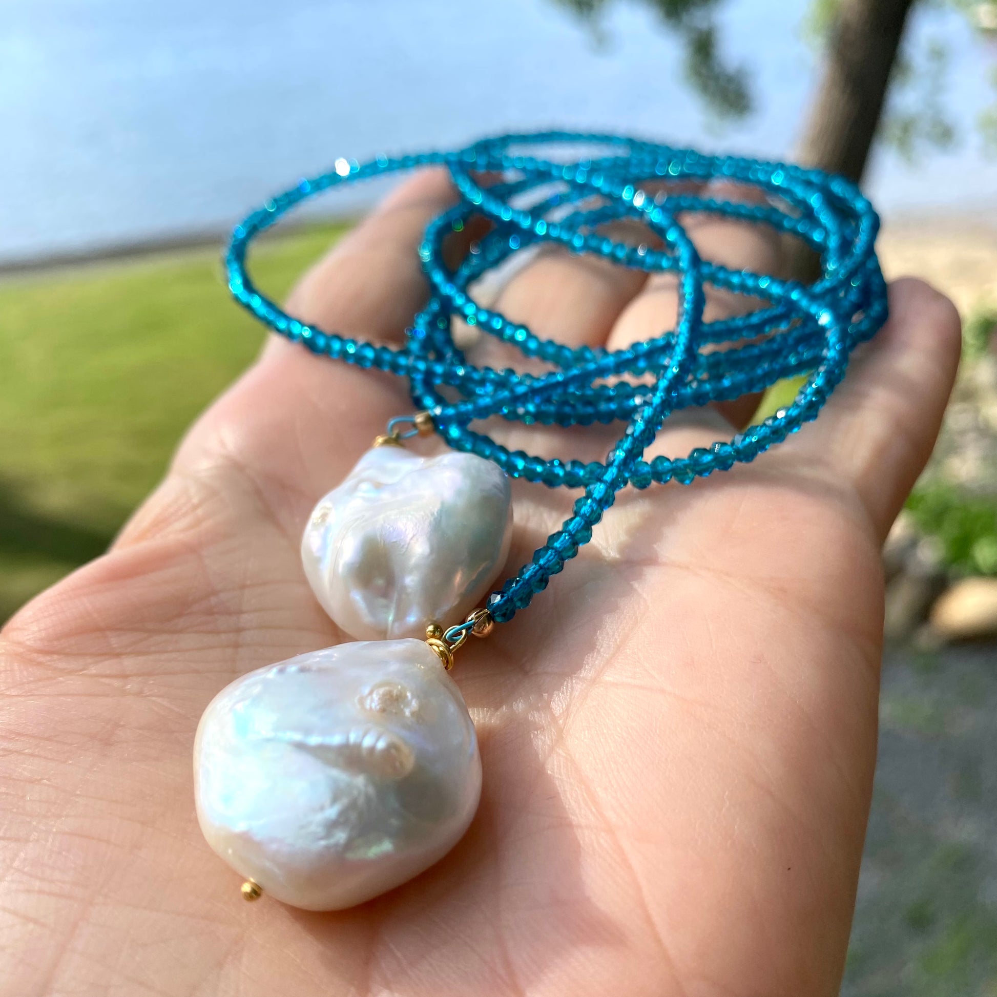 London Blue Quartz Lariat Necklace close-up in hand, blue faceted bead strand with large baroque pearl