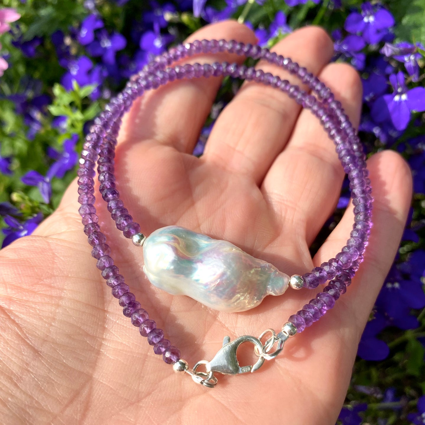 Stunning Purple Necklace featuring faceted Amethyst beads and a Large White Baroque Pearl centerpiece. A thoughtful February Birthstone Personalized Gift For Her. Crafted with Sterling Silver, the necklace measures 17 inches in length