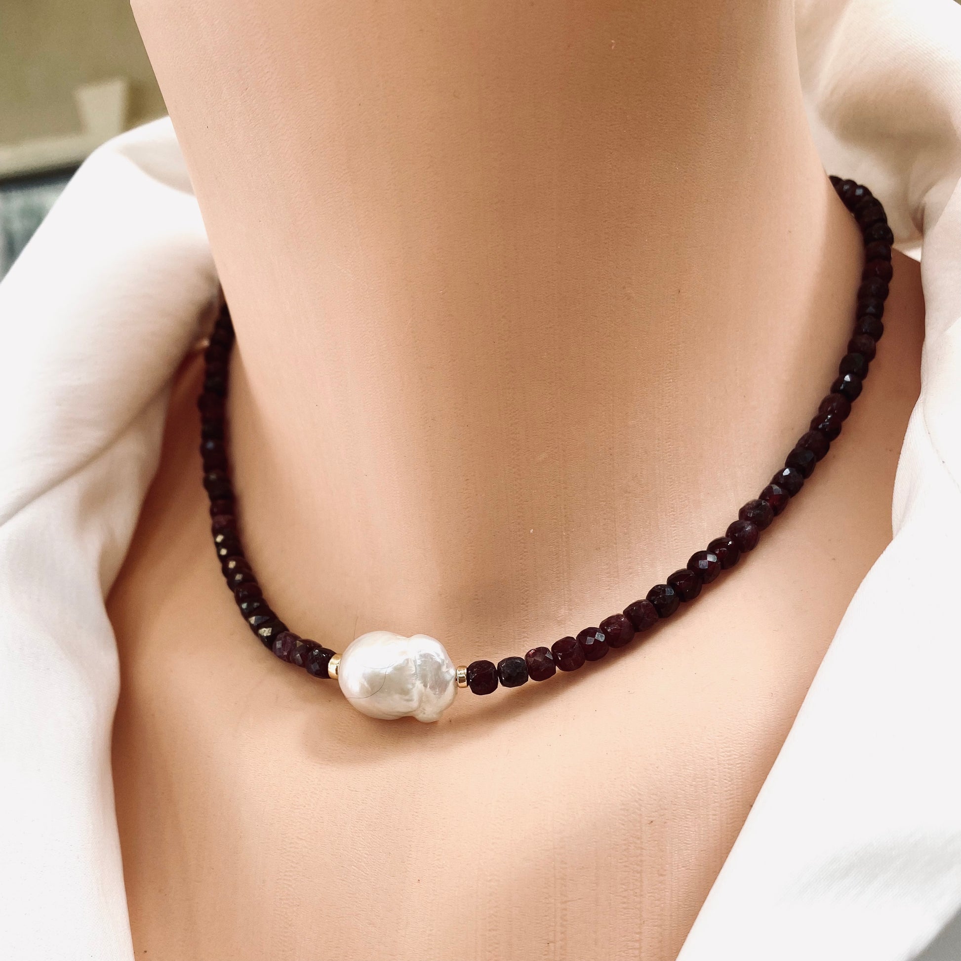 Garnet pearl necklace worn at the neckline with delicate garnet beads and baroque pearl
