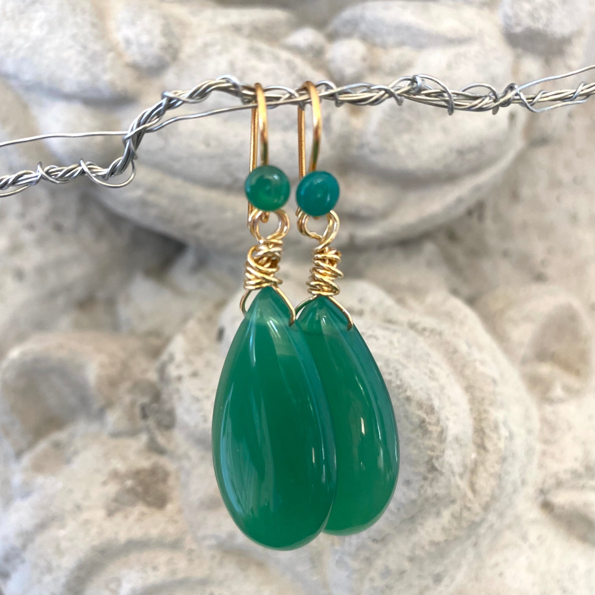 Emerald green onyx teardrop earrings photographed close up with gold plated details