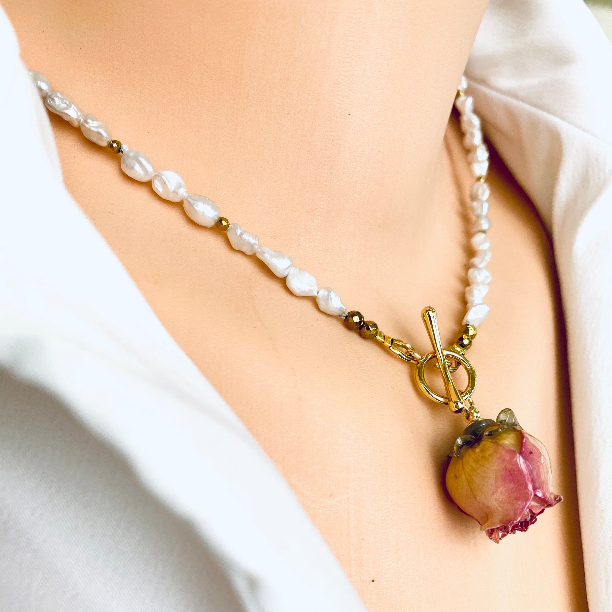 Side view of real pink rosebud pearl necklace showing preserved flower pendant and pearl strand