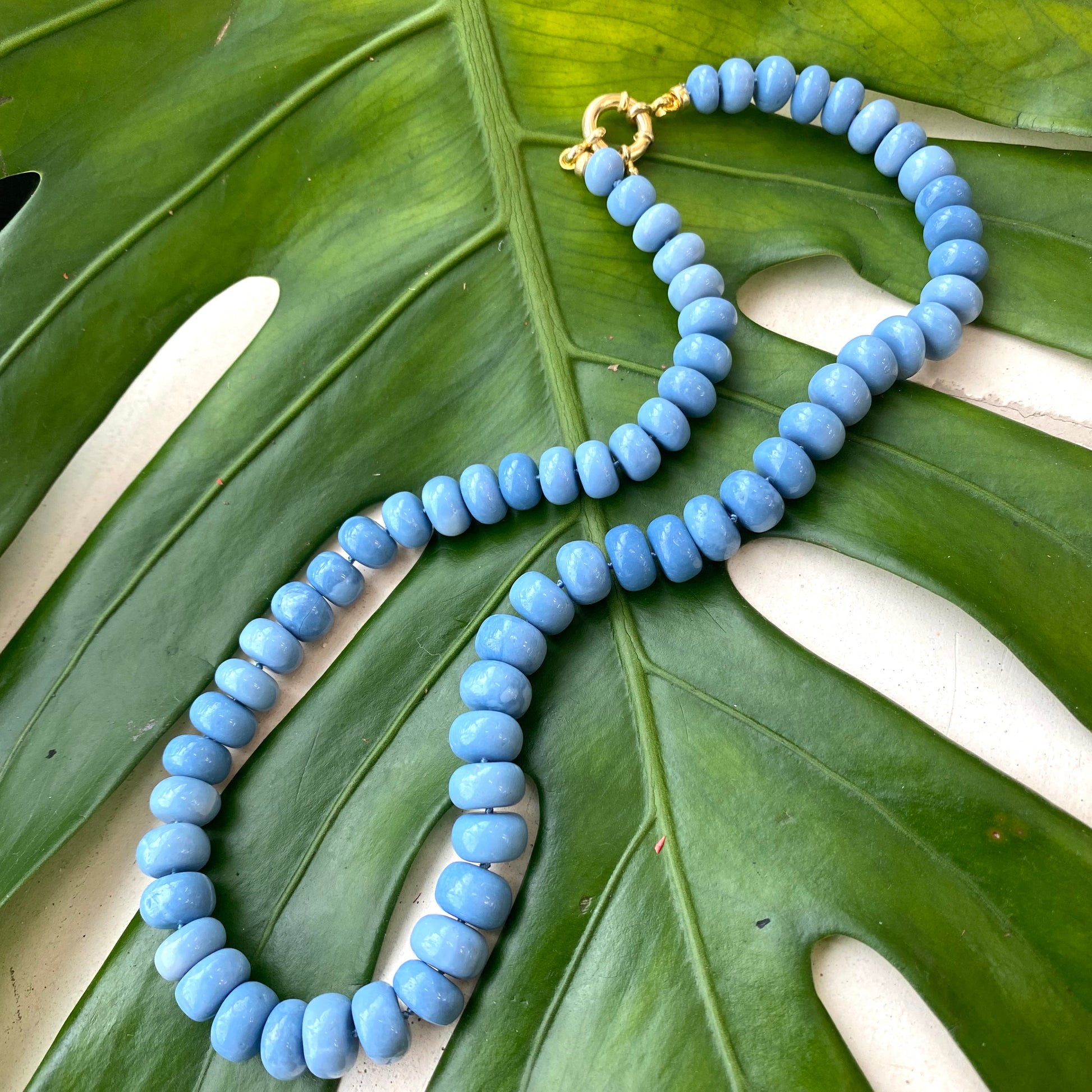 Blue opal necklace laid on tropical leaf, Oregon blue opal beads and marine clasp detail