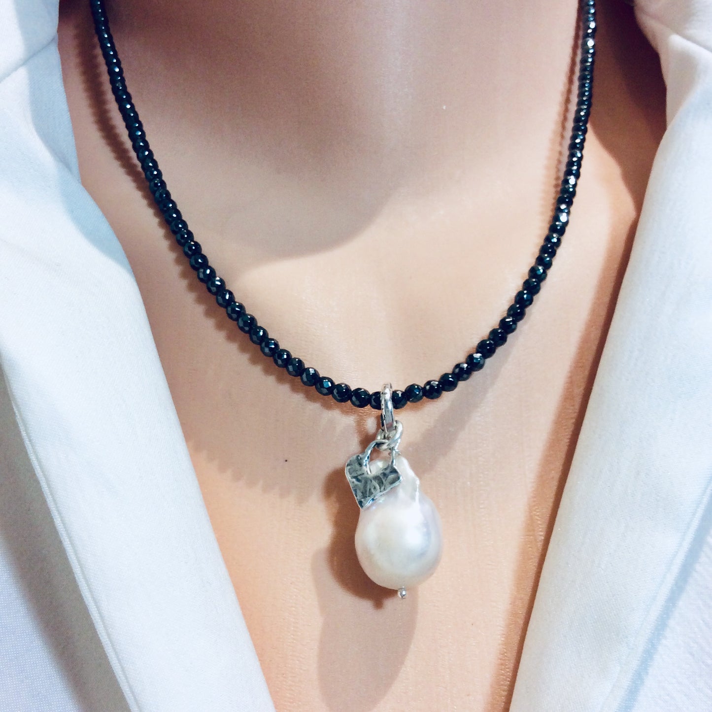 Hematite necklace with baroque pearl pendant worn on model sitting at the collarbone