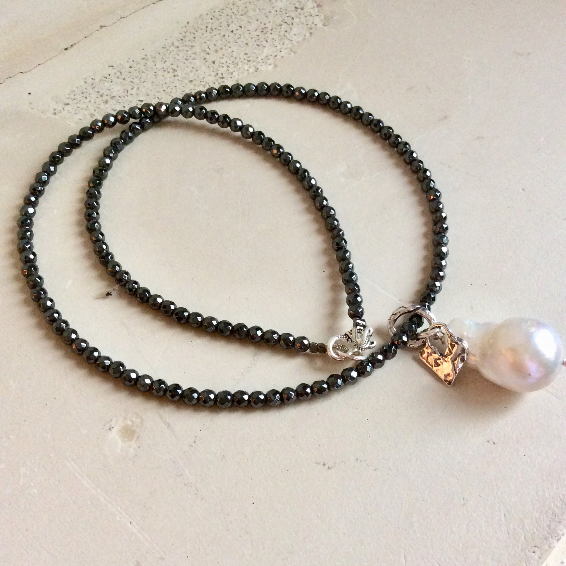 Hematite necklace with baroque pearl pendant showing floating pearl and charm detail