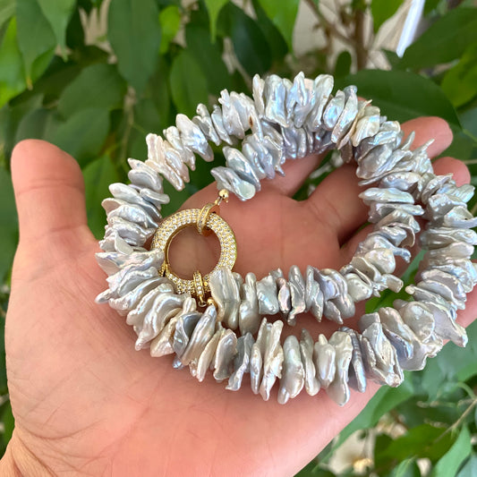 Keshi pearl choker necklace showcasing chunky grey pearls in hand with gold clasp.