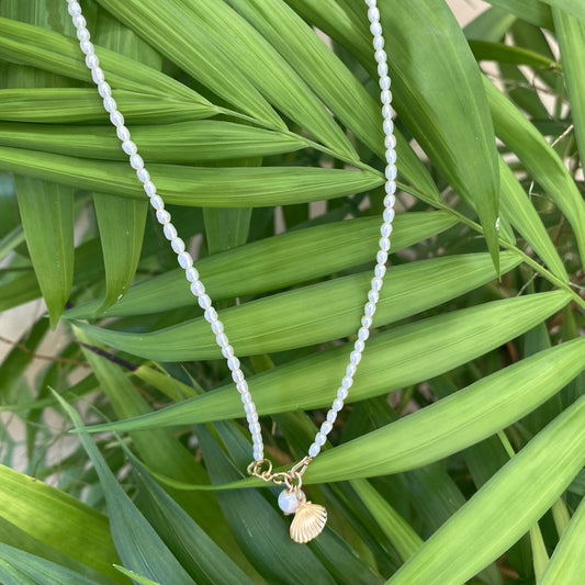 Pearl necklace with sea shell charm, handmade in Canada, featuring mini rice freshwater pearls on a tropical background.