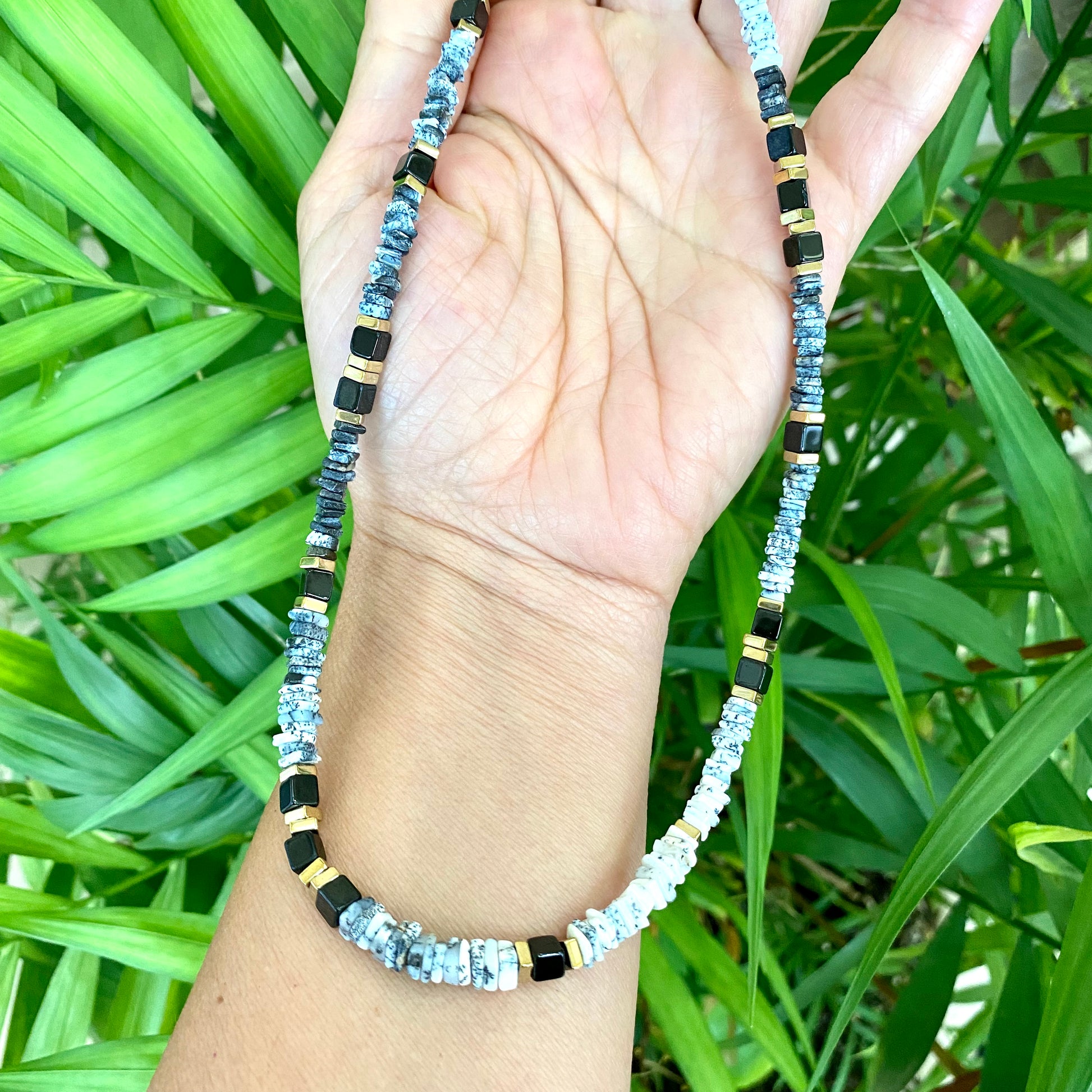 Dendritic opal necklace flat lay on wood surface, black white opal beads with spinel accents