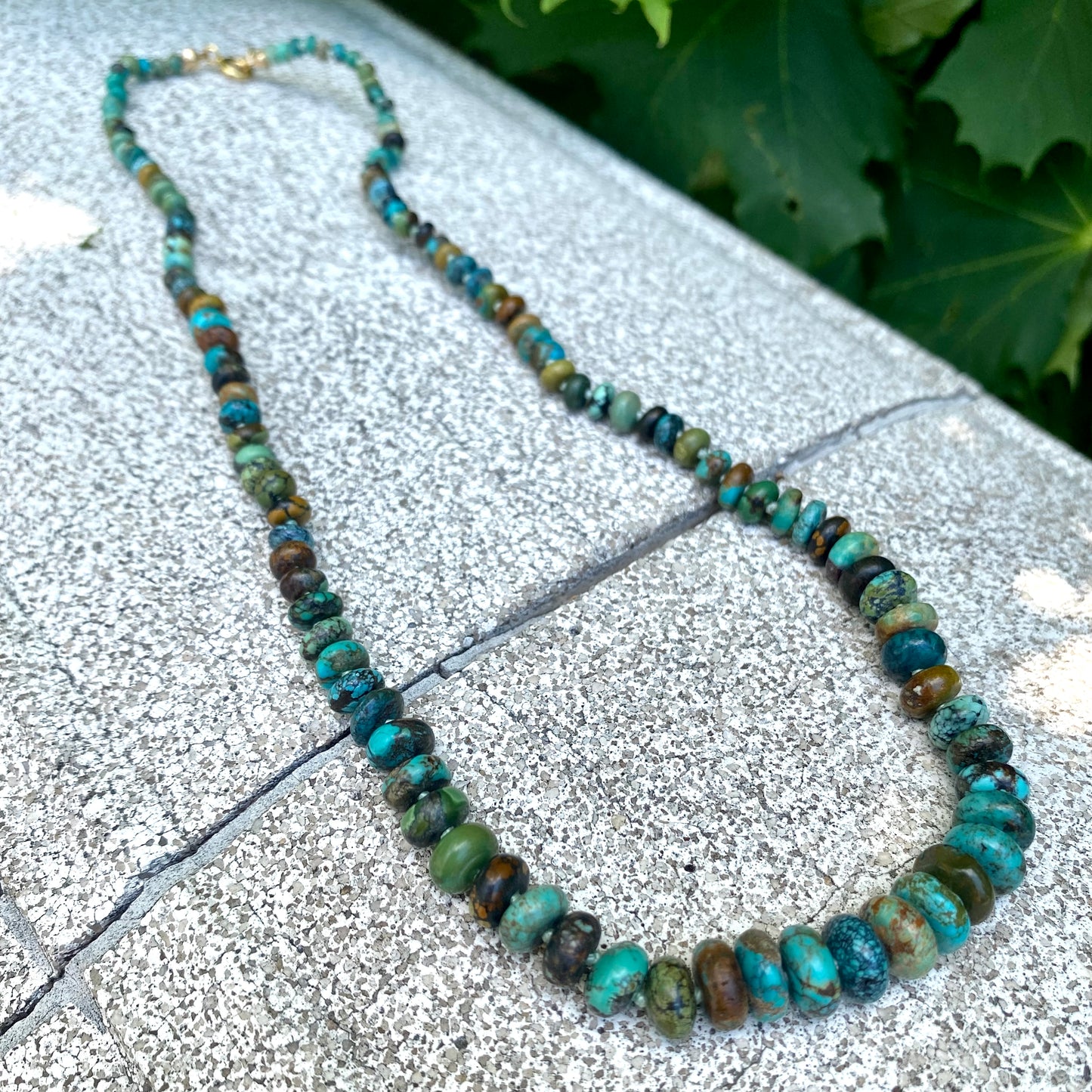Turquoise necklace gold filled laid on stone surface, graduated turquoise rondelle beads detail