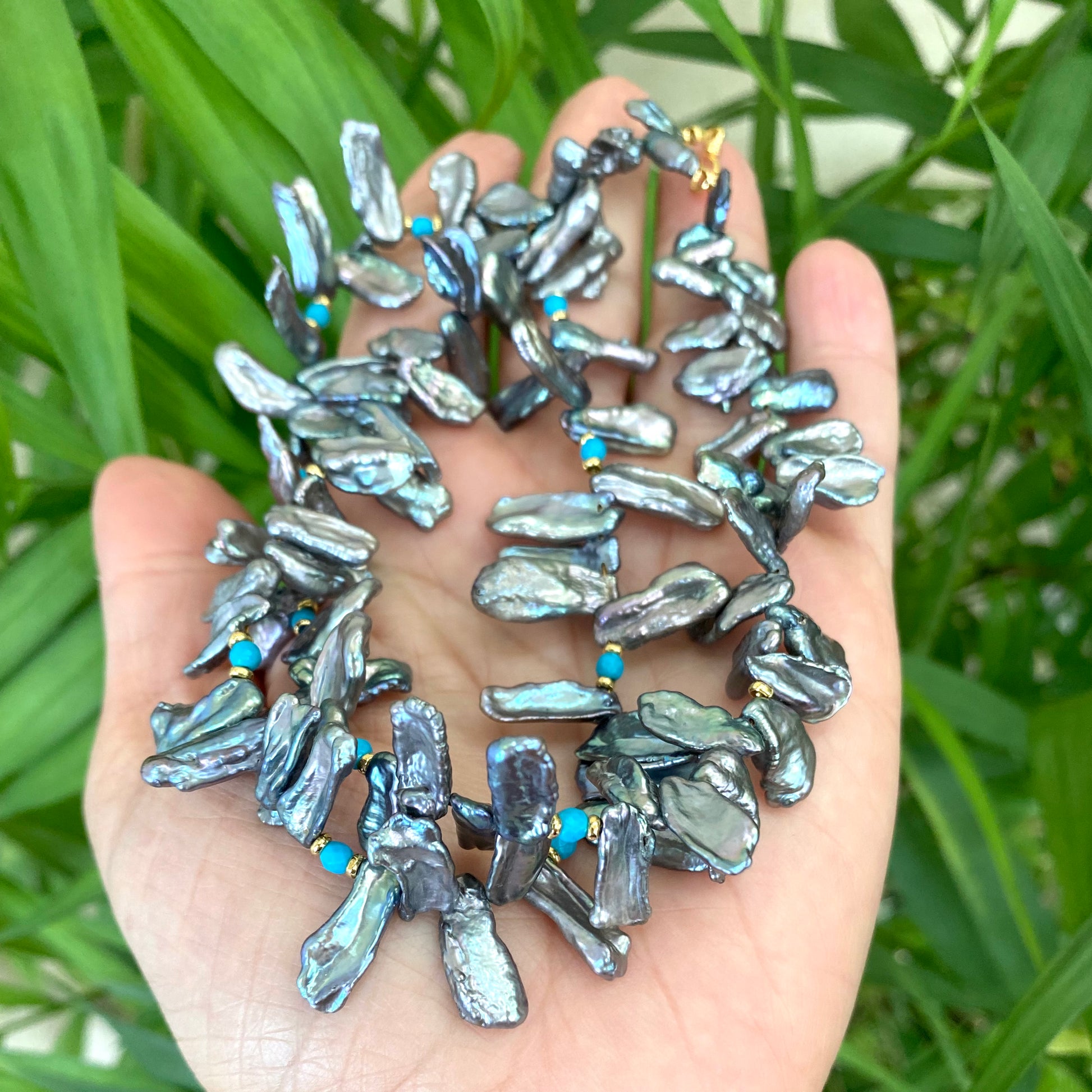 Biwa pearl turquoise necklace in hand, blue grey keshi pearls showing iridescent luster and turquoise beads