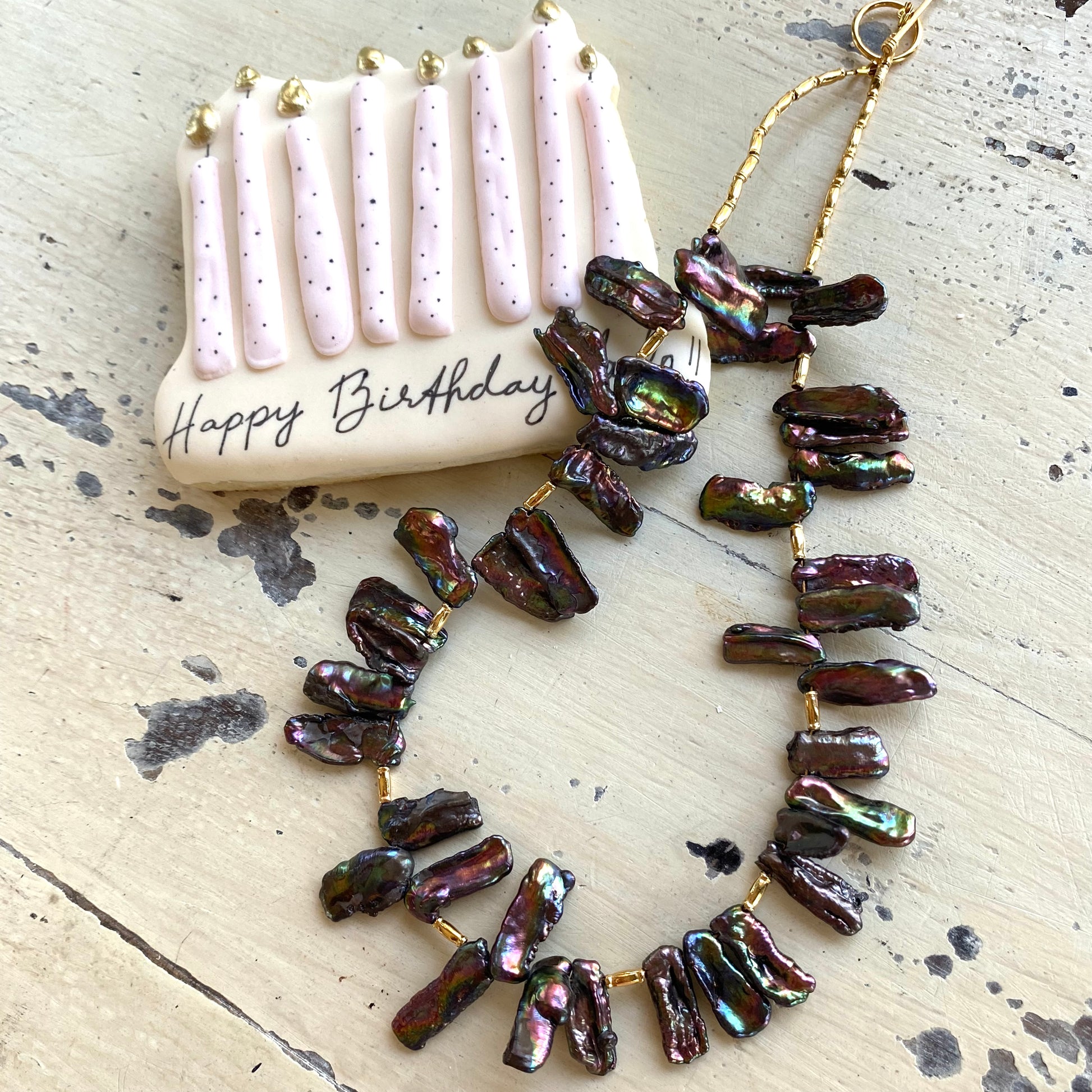 Black pearl choker necklace styled flat lay with packaging, peacock Biwa stick pearls and toggle clasp