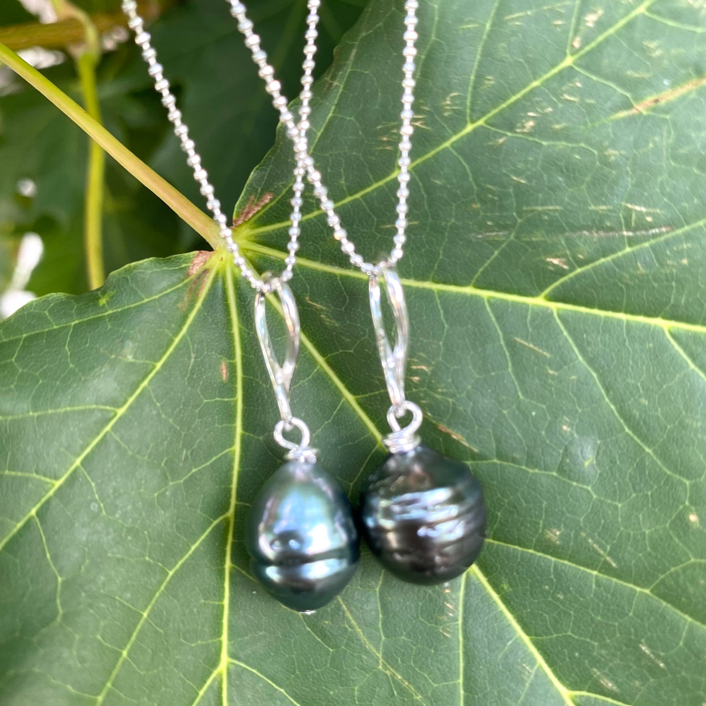 Tahitian teardrop pearl pendant necklace on green leaf background, sterling silver ball chain and pearl pendant