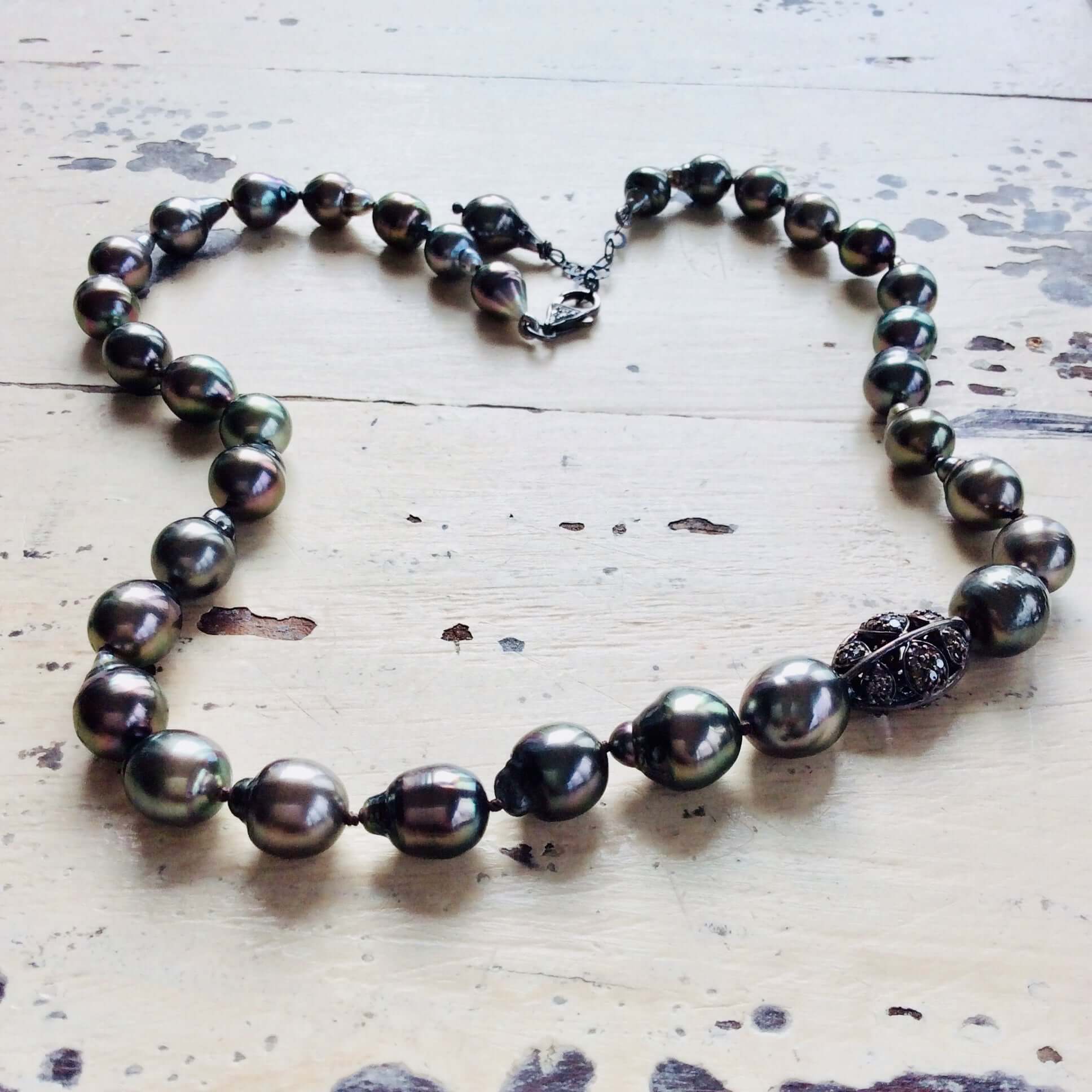Tahitian baroque pearl necklace with champagne diamonds on a wooden surface.