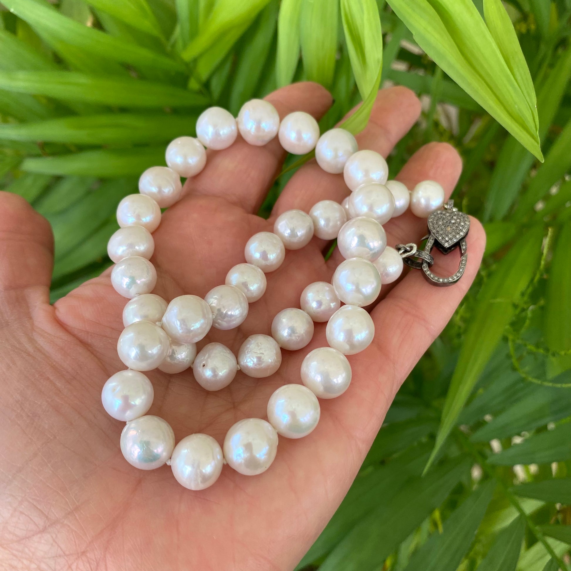 Edison pearl necklace with heart pavé diamond clasp, showcasing luxurious freshwater pearls in a hand-held display.
