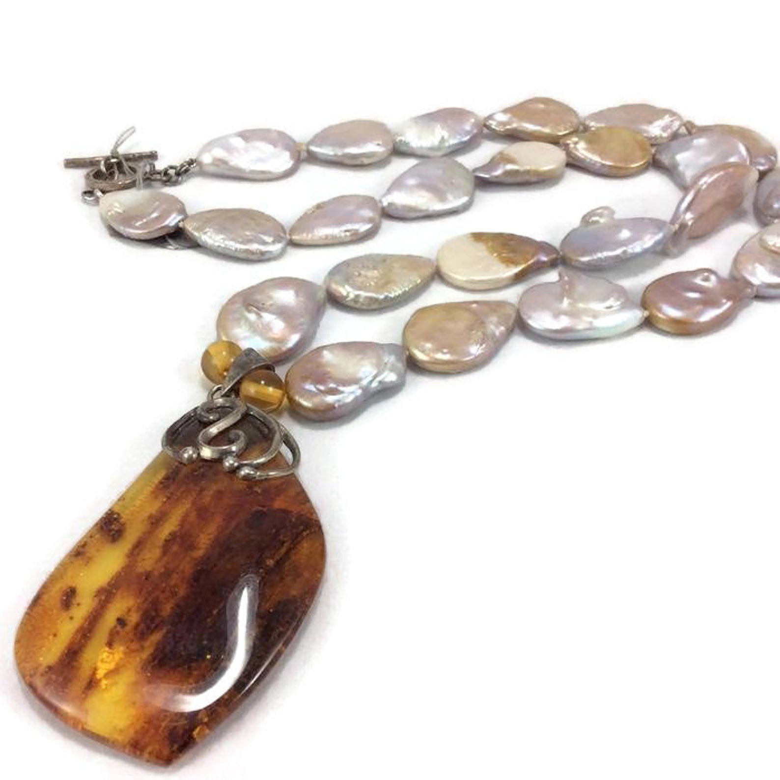 Flat tear-shaped keshi pearl necklace with amber pendant on white background, elegant jewelry.