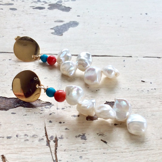 Baroque Keshi Pearl Earrings with gold dangle and turquoise, red coral accents on a rustic background.