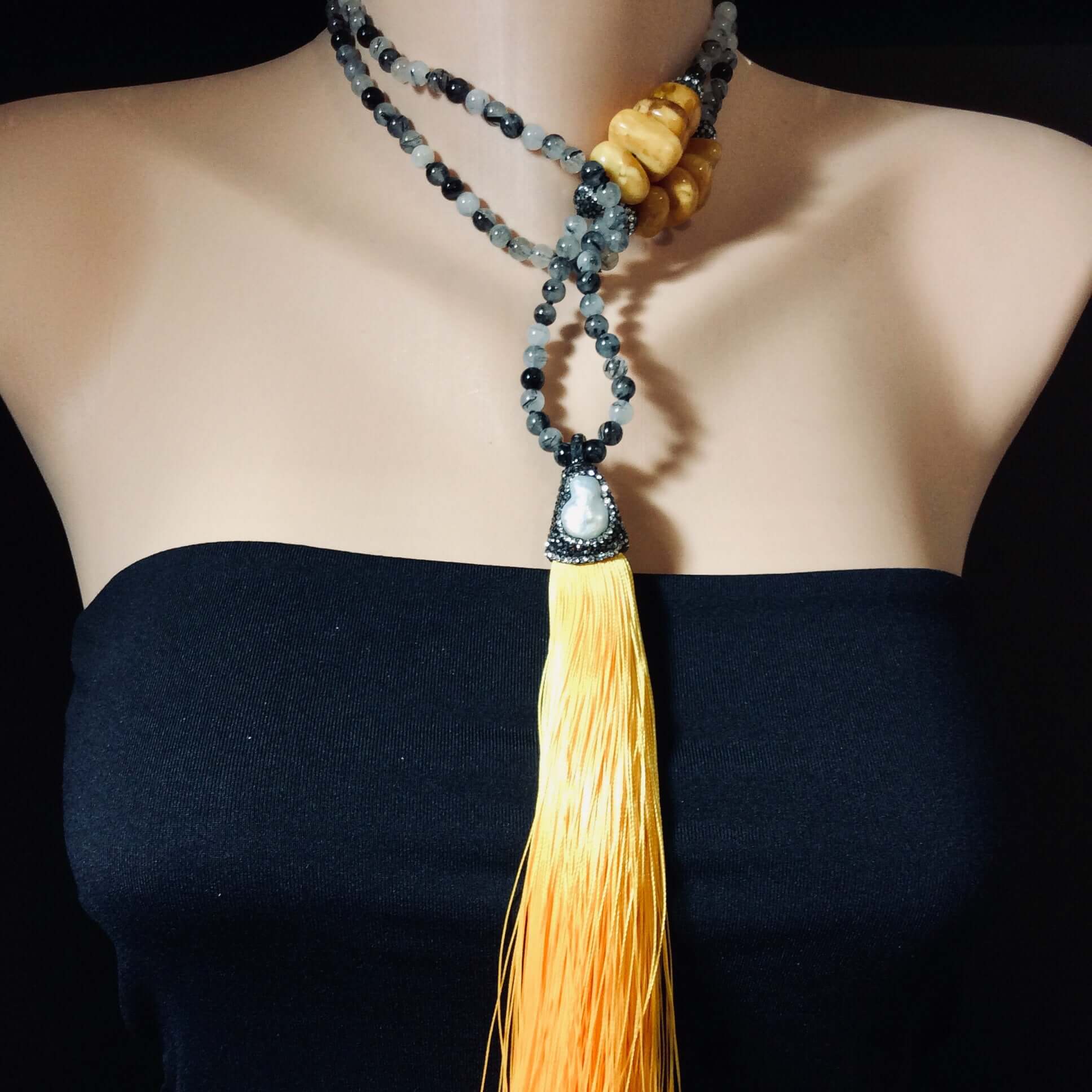 Rutilated quartz necklace with yellow tassel worn by mannequin, boho gemstone jewelry.